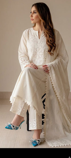 Woman wearing a white embroidered outfit with a matching shawl indoors.